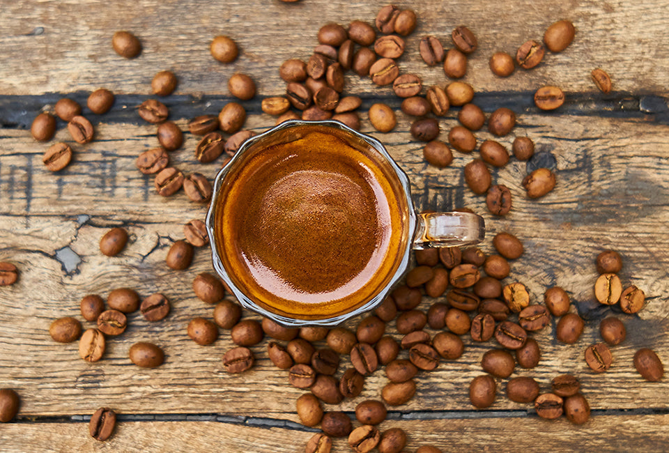 Cuban coffee in cup with coffee beans on wooden table