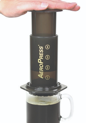 AeroPress coffee maker with a hand holding the top chamber on a white background