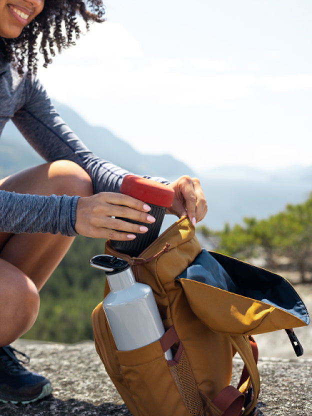 Woman packing AeroPress Go into yellow backpack