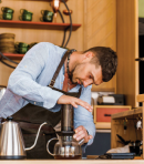 Barista with apron pressing AeroPress