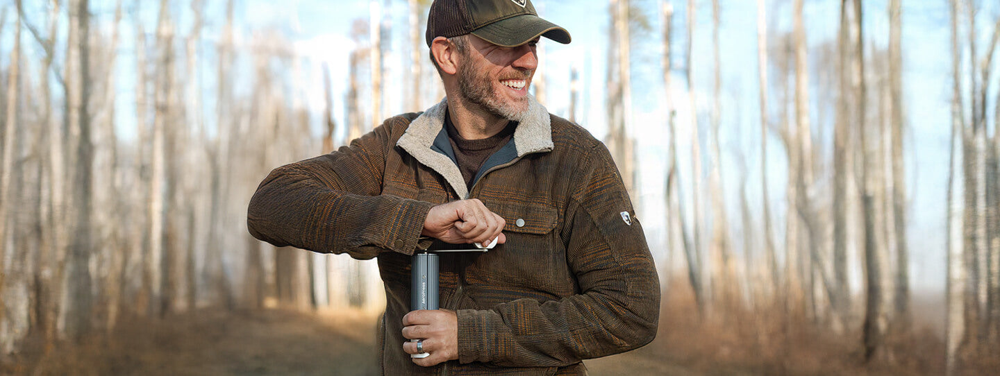 Person using manual coffee grinder outdoors