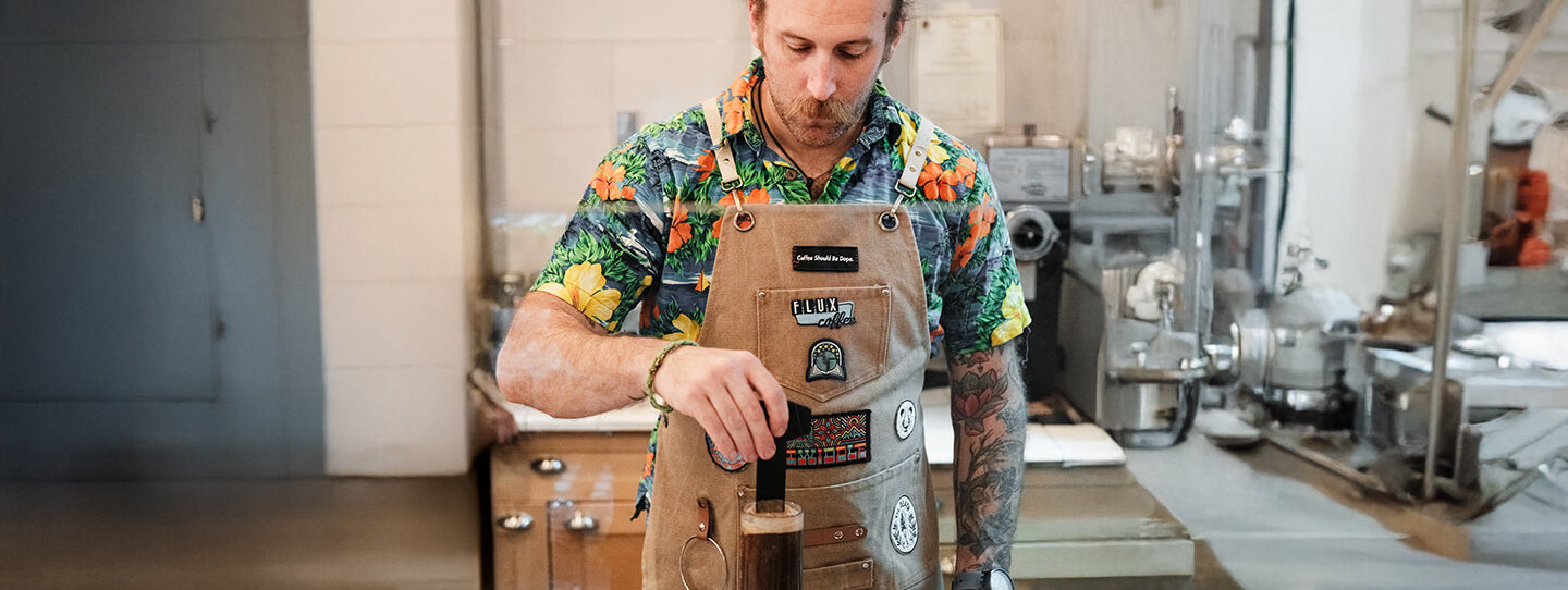 Barista brewing coffee with an AeroPress coffee maker in a coffee lab setting