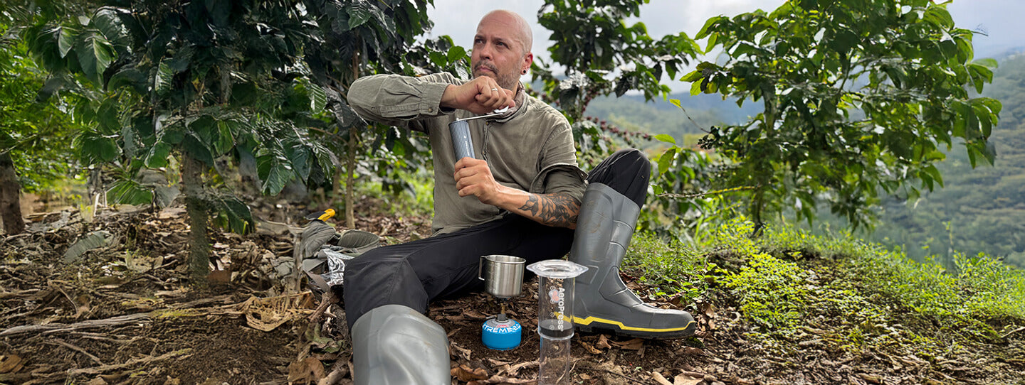 Person grinding coffee outdoors on a coffee farm