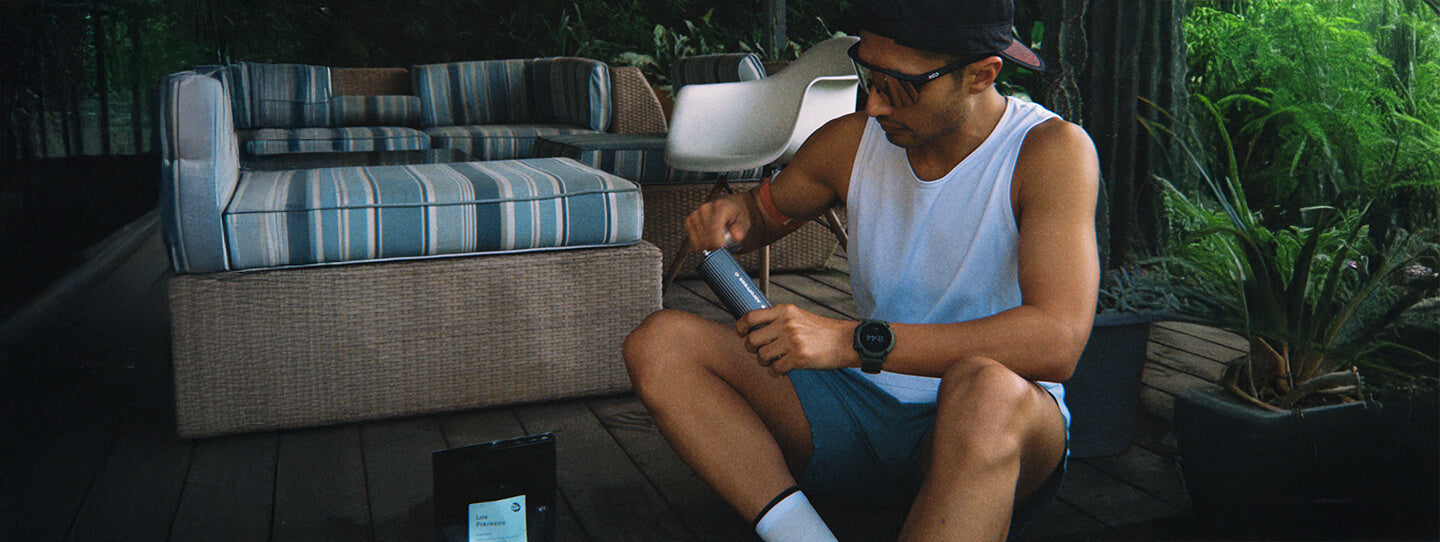 Man grinding coffee with a manual coffee grinder on a porch