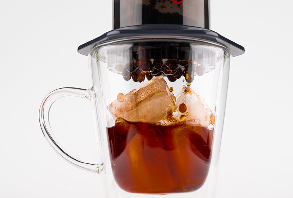AeroPress Original on clear glass mug brewing hot coffee over ice