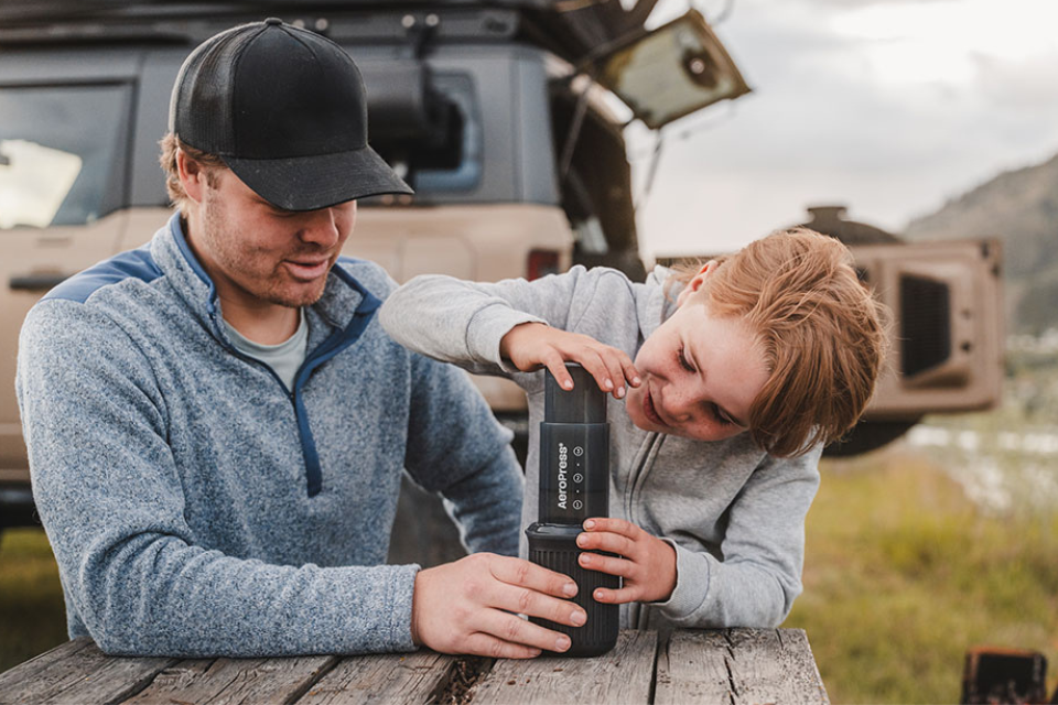 •	Father and son enjoying a coffee while camping with AeroPress Go 
