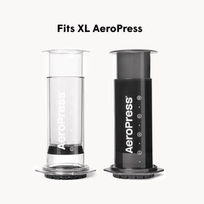 Two AeroPress XL coffee brewing devices, one clear and one black, on a white background.
