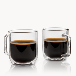 Two clear glass mugs filled with black coffee on a white background