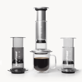 AeroPress coffee maker lineup with a cup of coffee on a white background