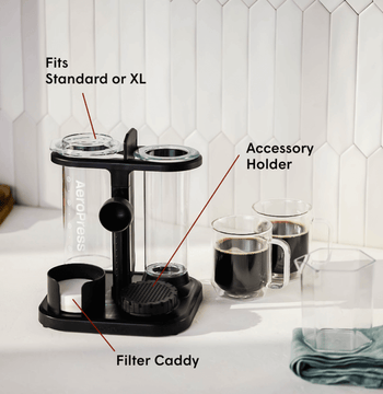 Black coffee accessory holder with labeled parts on a kitchen counter.