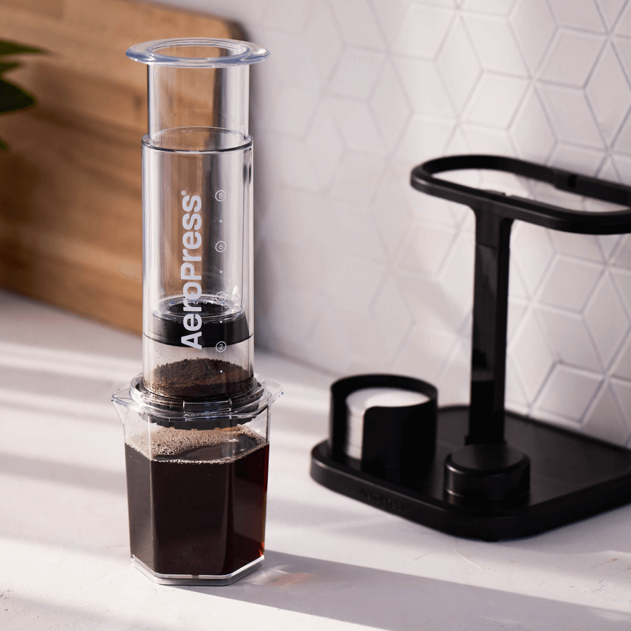 AeroPress coffee maker with brewed coffee on a kitchen counter with the AeroPress Organizer Stand