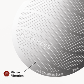 Close-up of a metallic surface with 'Aeropress' branding and text indicating micro-filtration and stainless steel material.