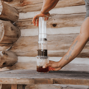 Person using an AeroPress Clear XL coffee maker in a cabin