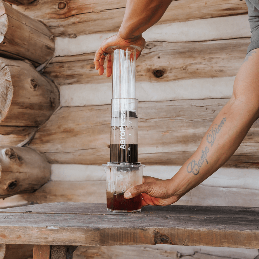 Person using an AeroPress Clear XL coffee maker in a cabin