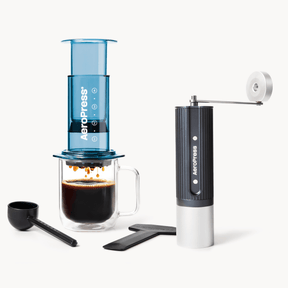 Aeropress coffee maker with a glass of brewed coffee and a manual grinder on a white background #color_Blue