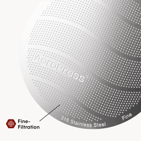 Close-up of an AeroPress coffee maker with 'AeroPress' branding and text indicating 316 stainless steel and fine filtration. #color_black