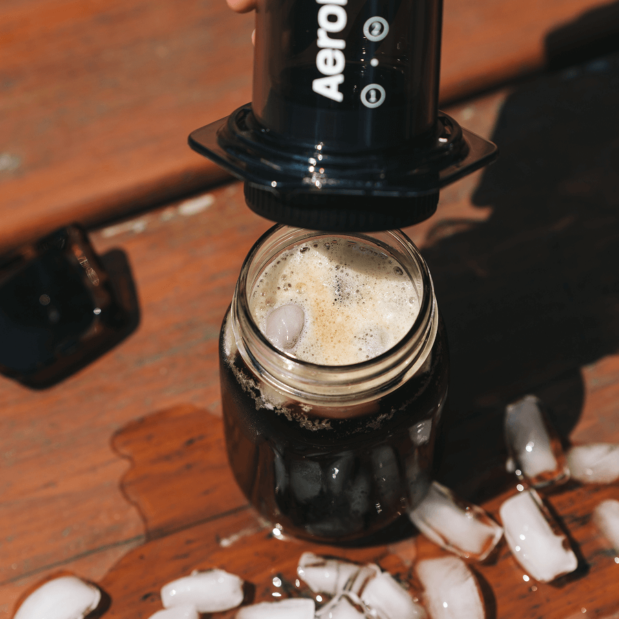 Aeropress being used to make iced coffee on a wooden surface. #color_black