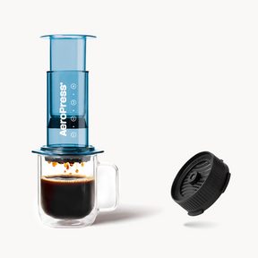 AeroPress Clear Blue coffee maker with a cup of coffee and a Flow Control Filter Cap on a white background #color_blue