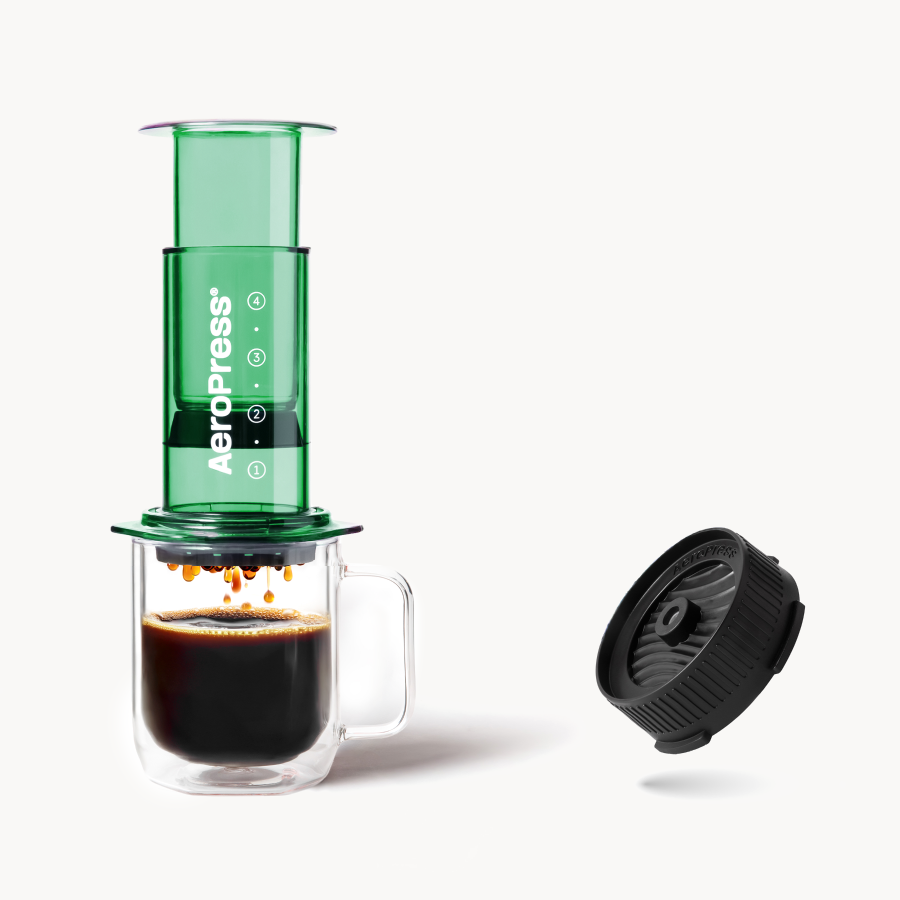 Green AeroPress Clear coffee maker with a clear mug of coffee and Flow Control Cap on a white background #color_green