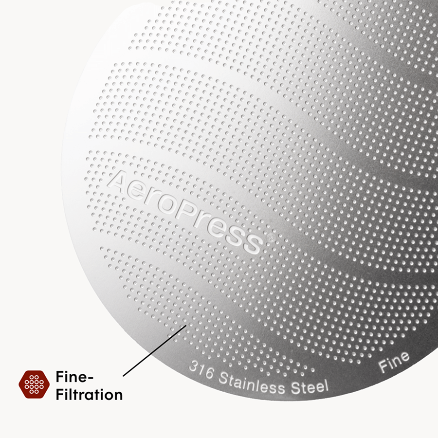 Close-up of an AeroPress coffee maker with 'AeroPress' branding and text indicating 316 stainless steel and fine filtration.  #color_purple