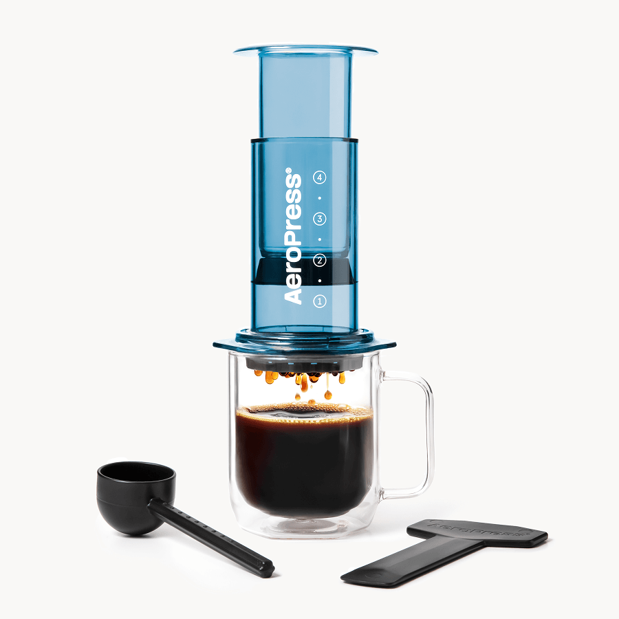 AeroPress coffee maker with a glass mug of brewed coffee on a white background #color_blue