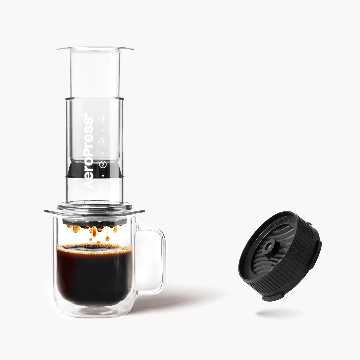 Aeropress coffee maker with a cup of coffee and a black filter on a white background Clear Pink #color_clear