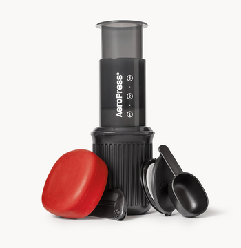 AeroPress Go coffee maker with red lid and black scoop on a white background