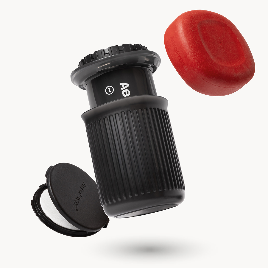 AeroPress Go coffee maker with red lid and black scoop on a white background