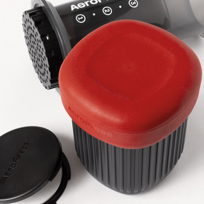 AeroPress Go coffee maker with red lid and black scoop on a white background