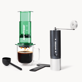 Aeropress coffee maker with a green chamber, black handle, and white base on a white background. #color_Green