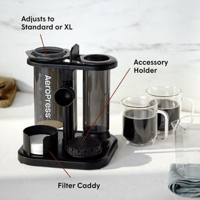 AeroPress coffee maker loaded into the Organizer Stand next to two mugs of coffee on a kitchen counter