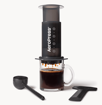 AeroPress Original coffee maker with a glass of brewed coffee on a white background