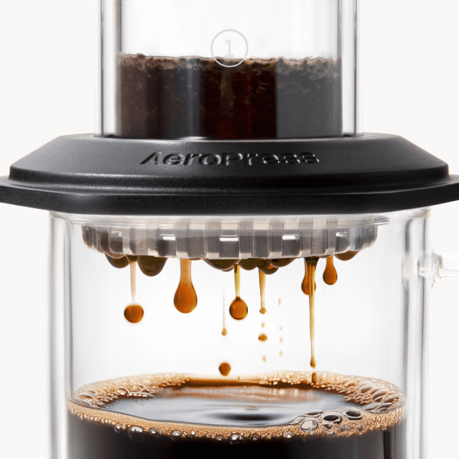 AeroPress Premium coffee maker with coffee being pressed through, showing the brewing process. #color_black