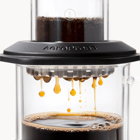 AeroPress Premium coffee maker with coffee being pressed through, showing the brewing process. #color_black