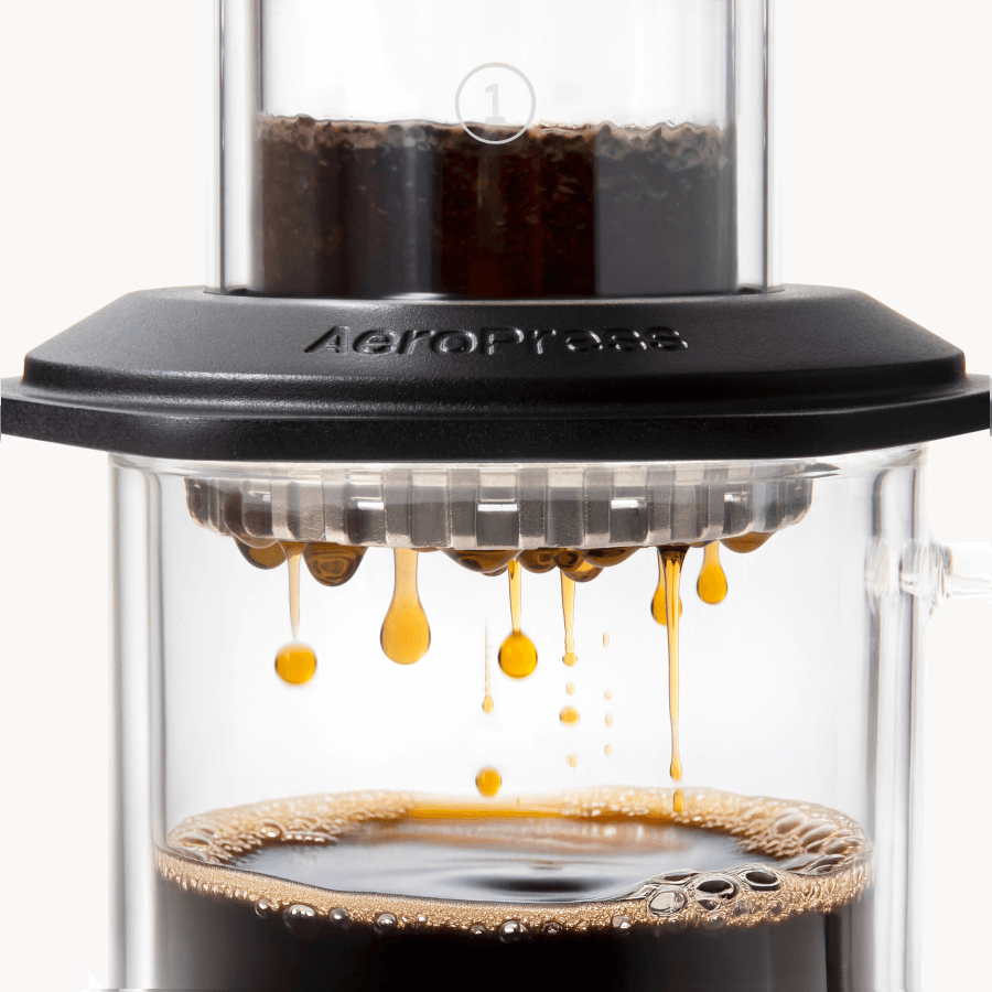 AeroPress Premium coffee maker with coffee being pressed through, showing the brewing process. #color_black
