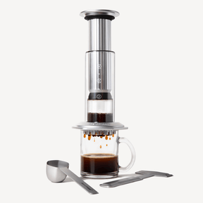 AeroPress Premium Coffee maker with a glass mug filled with coffee on a white background