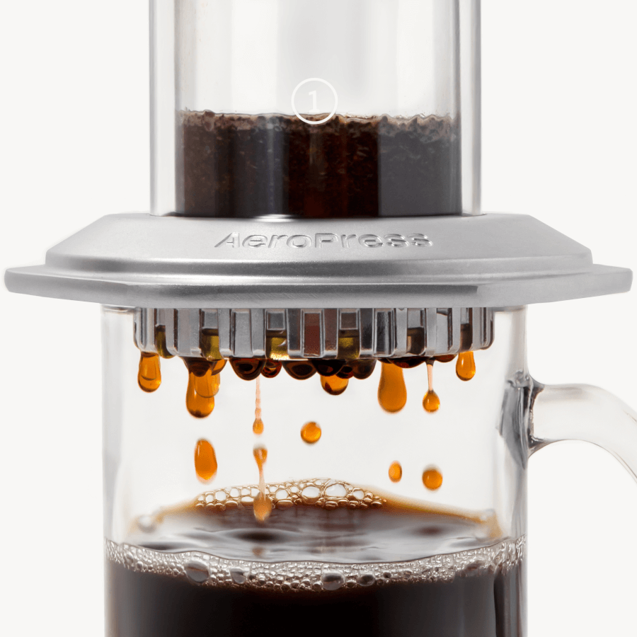AeroPress Premium coffee maker with coffee being pressed through, on a white background