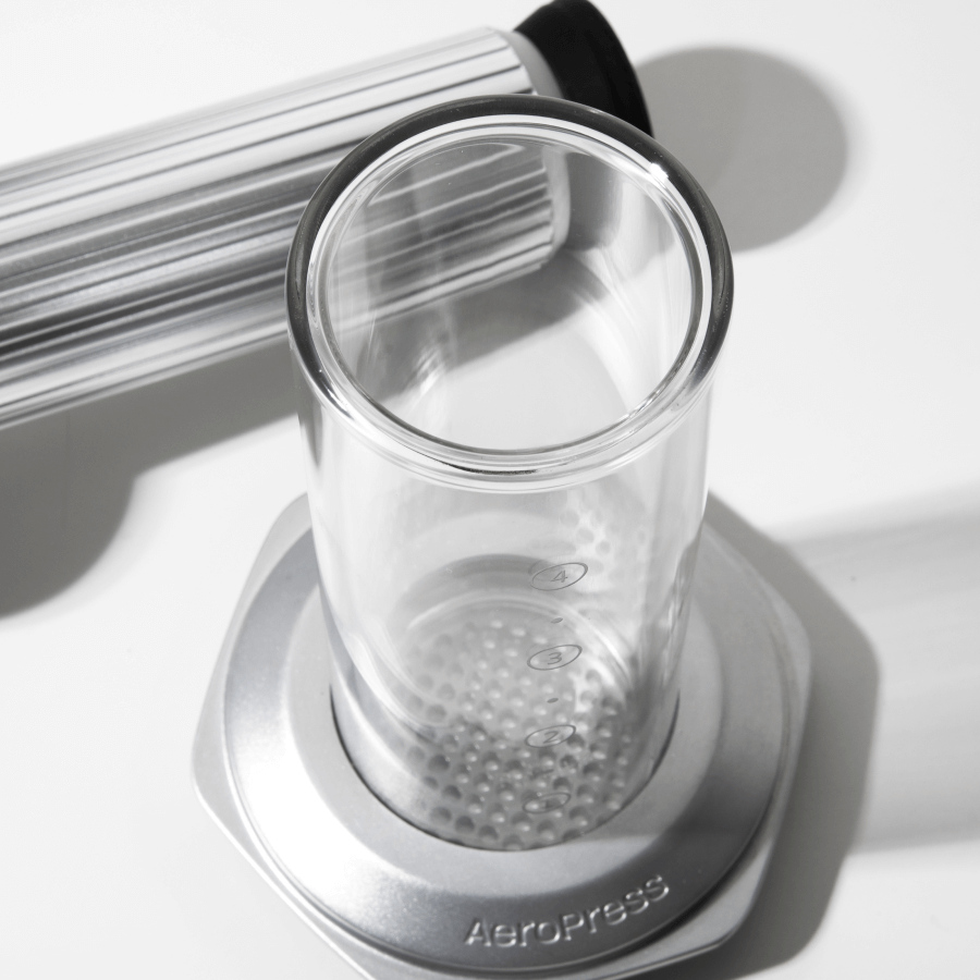 Clear glass AeroPress Premium chamber with metal base on a white  surface #color_silver