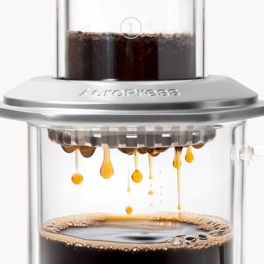 AeroPress Premium coffee maker with coffee being pressed through, showing the brewing process. #color_silver