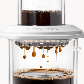 AeroPress Premium coffee maker with coffee being brewed, showing the process of making coffee. #color_white