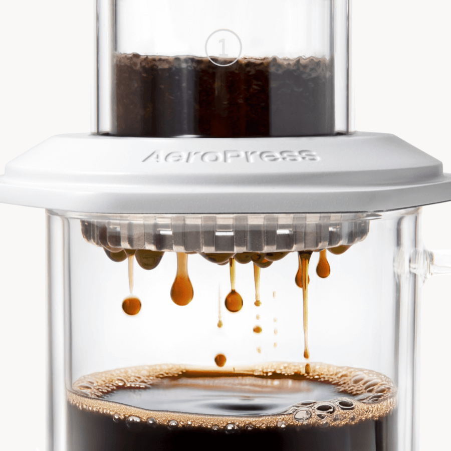 AeroPress Premium coffee maker with coffee being brewed, showing the process of making coffee. #color_white