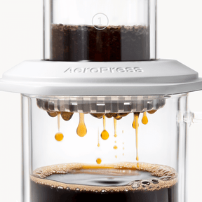 AeroPress Premium coffee maker with coffee being brewed, showing the process of making coffee. #color_white