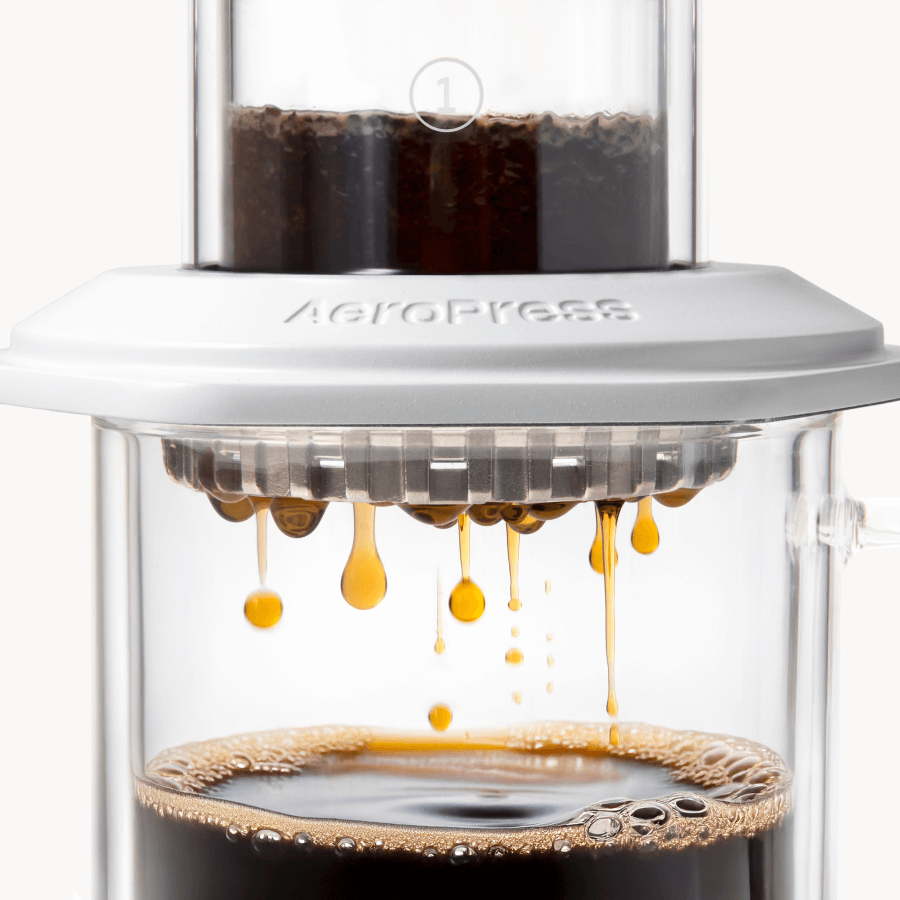 AeroPress Premium coffee maker with coffee being brewed, showing the process of making coffee. #color_white
