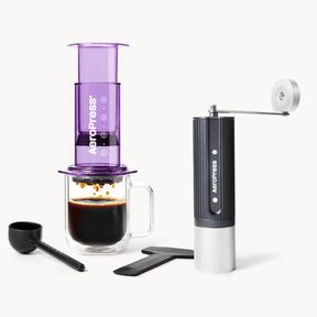 Aeropress coffee maker with a glass mug of coffee and a manual grinder on a white background #color_Purple