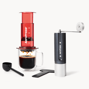 Aeropress coffee maker with a red canister, black and white handle, and a glass mug with coffee. #color_Red
