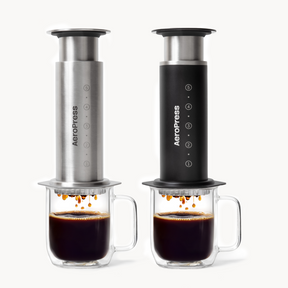 Two AeroPress coffee makers with cups of coffee on a white background #color_black
