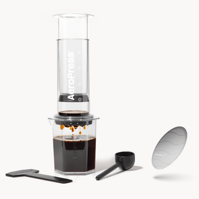 AeroPress coffee maker with a clear container, plunger, and filter on a white background