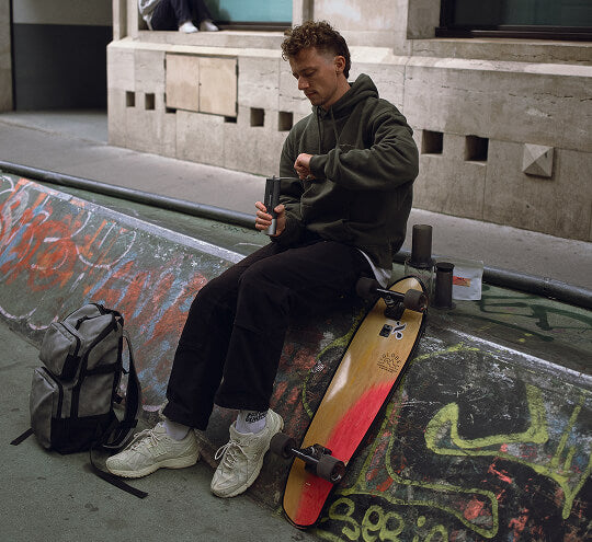 Person sitting with a skateboard on a graffiti-covered wall