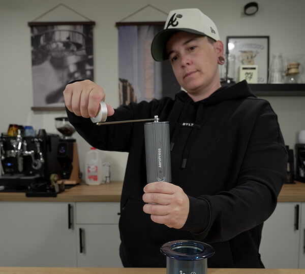 Person using a manual coffee grinder in a kitchen setting