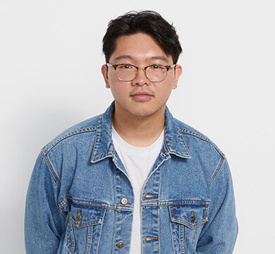 Person wearing a denim jacket and glasses on a white background